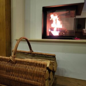 Kaminholzkorb aus Weide steht am Kamin